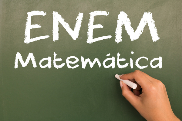 Mão escreve em quadro-negro: “Enem Matemática”.